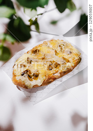 Mushroom and cheese flatbread served on a rustic table with greenery 129059807