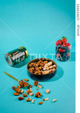 Healthy snack arrangement with granola, nuts, and fresh berries 129059945