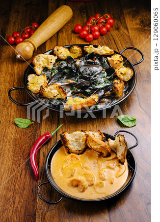 Delicious seafood dish served in traditional cookware with fresh ingredients Delicious seafood dish served in traditional cookware with fresh ingredients 129060065