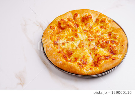 Cheese pizza on a black plate placed on a white marble surface Cheese pizza on a black plate placed on a white marble surface 129060116
