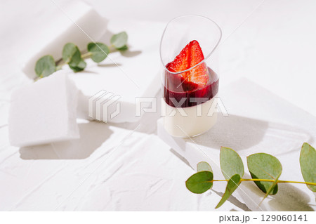 Layered dessert with strawberries and jelly on a bright surface 129060141