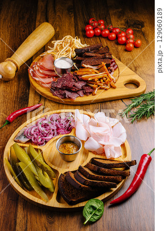 Charcuterie board with assorted meats and vegetables on wooden table 129060189
