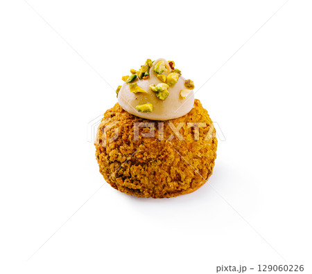Sweet pistachio dessert treats served on a white surface with creamy topping Sweet pistachio dessert treats served on a white surface with creamy topping 129060226