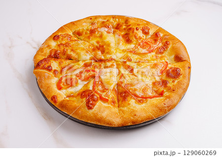 Freshly baked pizza with melted cheese and sliced tomatoes on display 129060269
