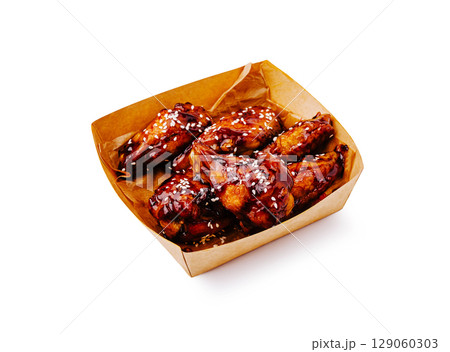 Crispy chicken wings with sweet glaze served in a takeaway box Crispy chicken wings with sweet glaze served in a takeaway box 129060303