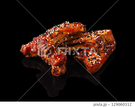 Juicy grilled ribs garnished with sesame seeds on a dark background 129060312