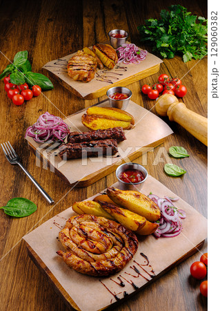 Delicious grilled dishes featuring meats and sides on wooden table Delicious grilled dishes featuring meats and sides on wooden table 129060382