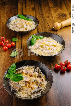 Delicious seafood pasta served on elegant black bowls garnished with herbs 129060383
