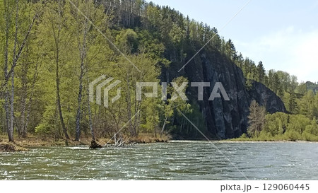 Idyllic River Landscape with Lush Green Forest and Rocky Cliff in Summer Season Day Light 129060445