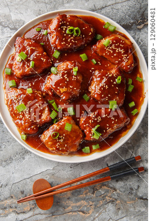Asian style sweet and sour pork chops close-up in a plate. Vertical top view Asian style sweet and sour pork chops close-up in a plate. Vertical top view 129060481