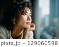 窓辺で物思いにふける女性のポートレート｜都会の景色とアンニュイな表情2 129060598