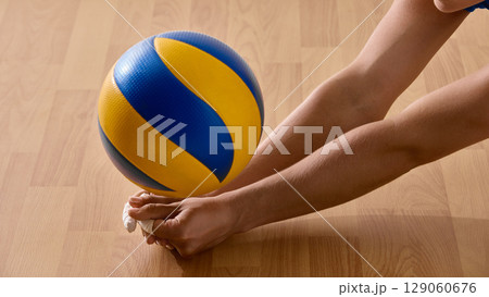 Volleyball athlete extending towards ball on wooden court, emphasizing hands and arms Volleyball athlete extending towards ball on wooden court, emphasizing hands and arms 129060676