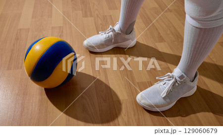 Athlete holding volleyball on indoor wooden court highlighting sportsmanship 129060679