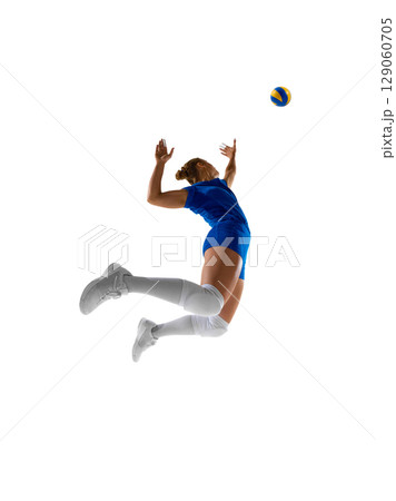 Blue-clad female volleyball athlete leaps for a strong spike in thrilling match 129060705