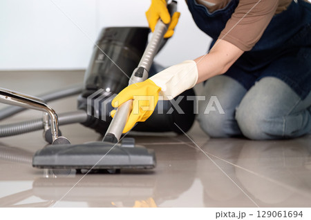 Floor Cleaning. Person vacuuming tiled floor with vacuum cleaner. 129061694