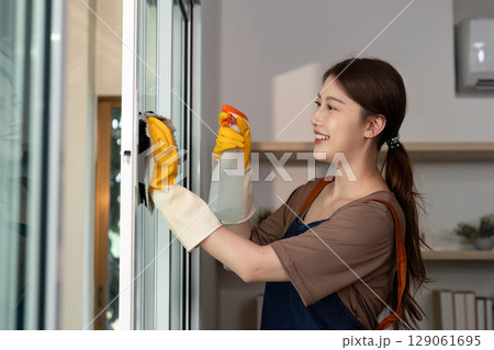 Home Cleaning. Young woman cleaning window with spray and cloth. Home Cleaning. Young woman cleaning window with spray and cloth. 129061695