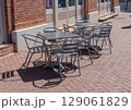 Outdoor metal tables and chairs on a sunny sidewalk cafe patio. 129061829