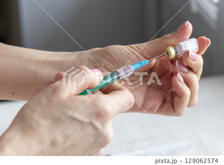 Close upshot of the woman preparing medicine for injection. 129062574
