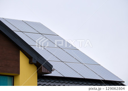 Private home roof covered with solar photovoltaic panels for generating of clean ecological electric energy in suburban rural town area. Concept of autonomous house 129062804