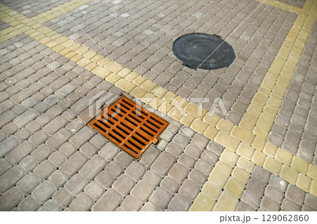 Old rusted metal gutter for rain water on the stone paved sidewalk. 129062860
