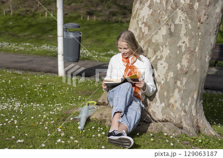Woman enjoying a book under a tree Woman enjoying a book under a tree 129063187