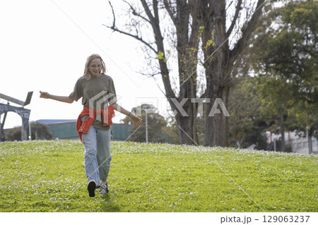 Young woman walking in park enjoying spring day Young woman walking in park enjoying spring day 129063237