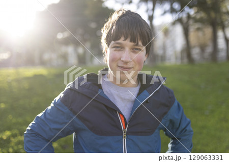 Portrait of smiling teenager posing in park during golden hour 129063331
