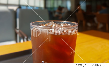 Glass of Iced Coffee on Cafe Table in Bright Sunlight 129063892