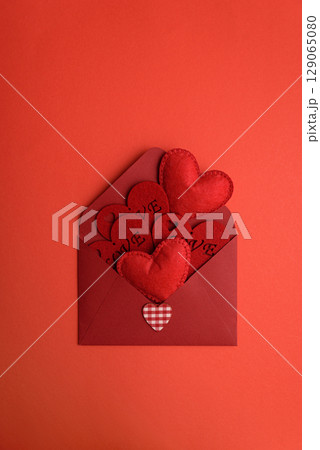 Open red envelope and red felt hearts on red background. Valentines day celebration 129065080