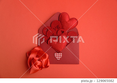 Open red envelope and red felt hearts on red background. Valentines day celebration Open red envelope and red felt hearts on red background. Valentines day celebration 129065082