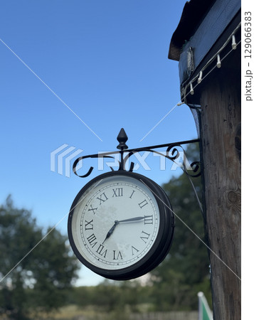Vintage clock on a wooden structure. Dial with Roman numerals. Vintage clock on a wooden structure. Dial with Roman numerals. 129066383