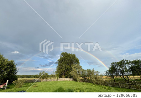 Double rainbow in the blue sky. Rural landscape. 129066385