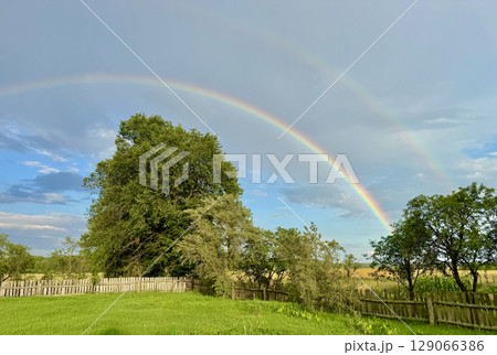 Double rainbow in the blue sky. Rural landscape. 129066386