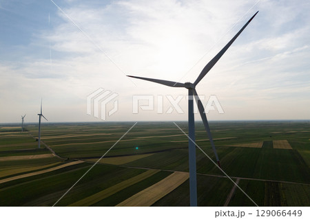Aerial view of wind turbine on an agricultural filed at sunset. Close up of blades. 129066449