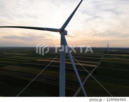 Aerial view of wind turbine on an agricultural filed at sunset. Close up of blades. 129066460
