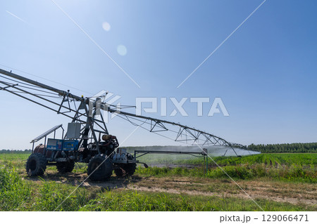 Autonomous machine is moving watering pivot along irrigation canal 129066471