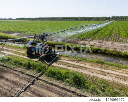 Autonomous machine is moving watering pivot along irrigation canal 129066472