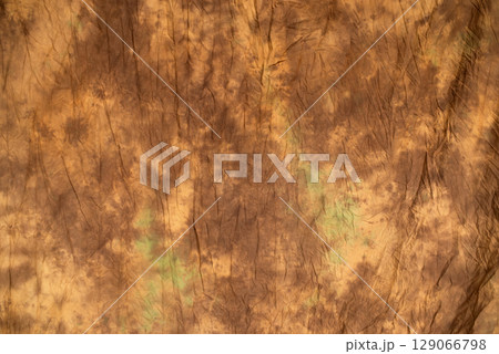 Brown wrinkled fabric texture with subtle green stains, abstract background for design, vintage or grunge style 129066798