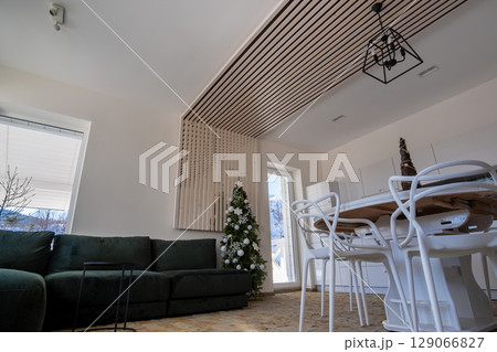 Interior of modern spacious kitchen with white walls, decorative wooden elements, contemporary furniture and big soft couch. Interior of modern spacious kitchen with white walls, decorative wooden elements, contemporary furniture and big soft couch. 129066827