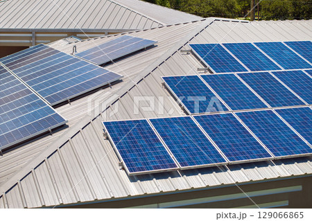 Home roof with blue solar photovoltaic panels for producing clean ecological electric energy. Investing in renewable electricity for retirement income Home roof with blue solar photovoltaic panels for producing clean ecological electric energy. Investing in renewable electricity for retirement income 129066865