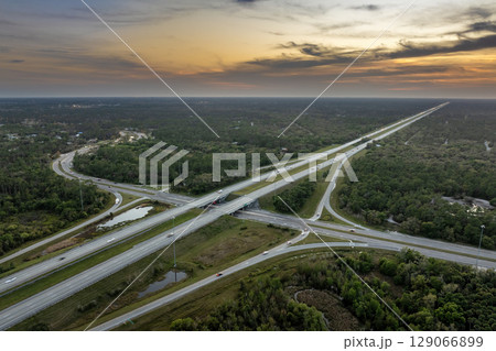 Freeway overpass junction in Florida with fast moving traffic cars and trucks in American rural area at sunset. Interstate transportation infrastructure in USA Freeway overpass junction in Florida with fast moving traffic cars and trucks in American rural area at sunset. Interstate transportation infrastructure in USA 129066899