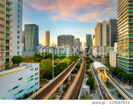 Elevated train system through Brickell district in Miami, Florida with city skyscrapers and sunset skies highlighting the public transportation network 129067013