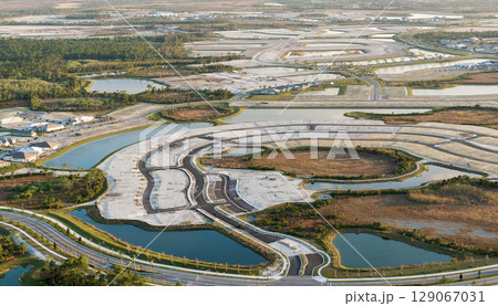 Development of real estate market in the USA. Aerial view of large construction site with building equipment on prepared soil in American rural area 129067031