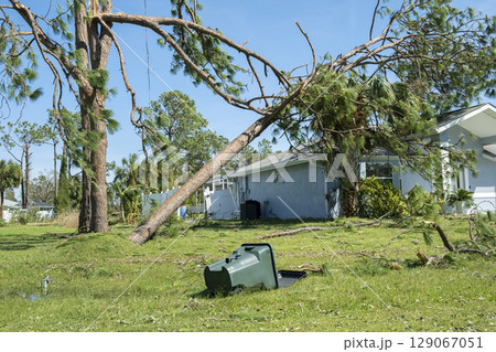 Damage to Florida house roof from uprooted tree after hurricane. Insurance claim on destroyed home. Aftermath of natural disaster concept Damage to Florida house roof from uprooted tree after hurricane. Insurance claim on destroyed home. Aftermath of natural disaster concept 129067051
