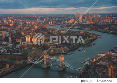 An aerial view of London's Tower Bridge with the River Thames reflecting sunset light. Canary Wharf's skyscrapers rise in the background during Christmas. An aerial view of London's Tower Bridge with the River Thames reflecting sunset light. Canary Wharf's skyscrapers rise in the background during Christmas. 129067281