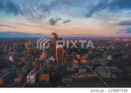 Aerial view of London during Christmas, featuring the Walkie Talkie building, modern skyscrapers, and the River Thames under a warm sunset glow. Aerial view of London during Christmas, featuring the Walkie Talkie building, modern skyscrapers, and the River Thames under a warm sunset glow. 129067286