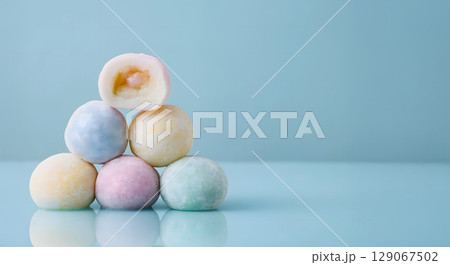 Soft rice cake pieces in pastel colors stacked on reflective surface, evoking sense of sweetness and delight 129067502