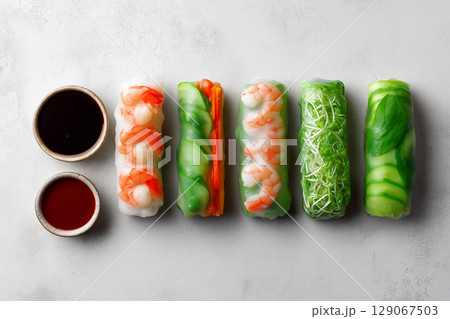 Fresh spring rolls filled with shrimp, vegetables, and herbs, served with dipping sauces, create vibrant and appetizing dish 129067503