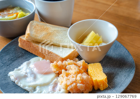 トーストと目玉焼き、明太ポテトやフルーツが並ぶ和洋ミックスの朝食 129067769
