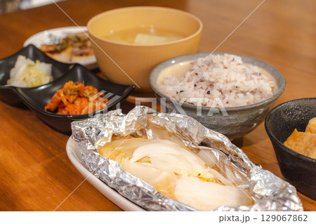 ホイル焼きと雑穀ごはん、味噌汁が並ぶ家庭的な和風夕食セット 129067862